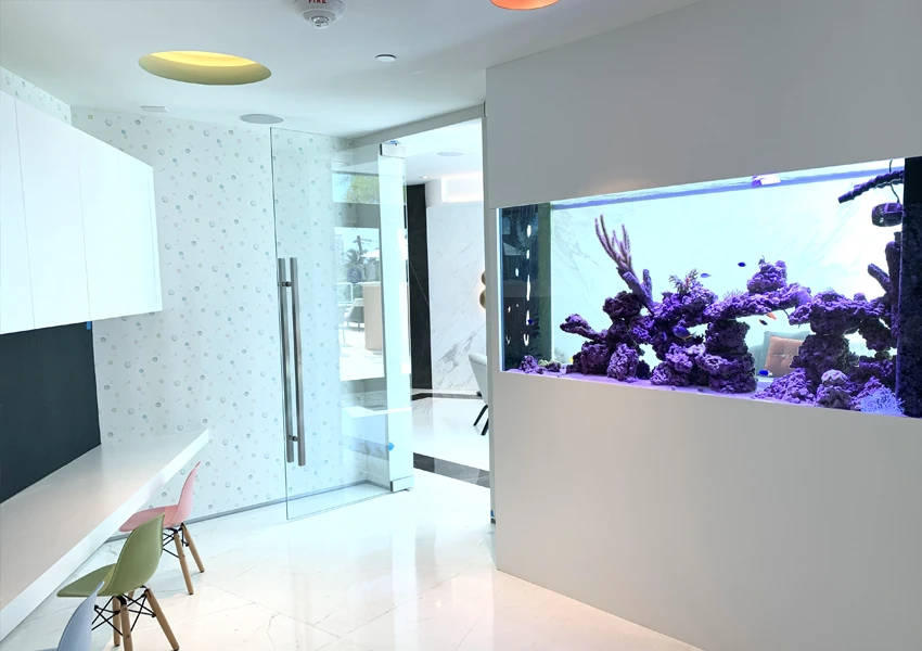 Large aquarium visible from both sides in a children’s playroom at a hotel.